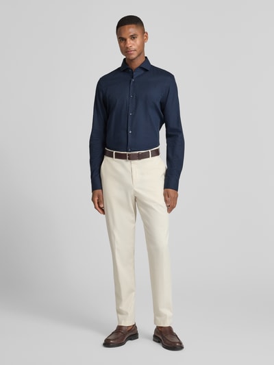 Männermodel trägt Slim Fit Businesshemd mit Haifischkragen von JOOP! Collection in Dunkelblau mit Allover-Print, Ganzkörperansicht von vorne. Hemd aus reiner Baumwolle, langärmelig, durchgängige Knopfleiste, abgerundeter Saum, Rückenlänge 76 cm, Schulterbreite 45 cm, Ärmellänge 67 cm.