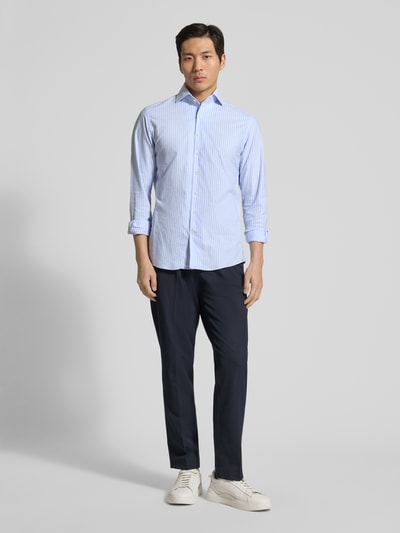 Męski model nosi Slim Fit Freizeithemd aus reiner Baumwolle Modell 'Oxford' od Profuomo w jasnoniebieskie paski, długi rękaw, krój slim fit, kołnierz kent, pełna długość guzików, długość pleców w rozmiarze 40: 73 cm, szerokość w rozmiarze 40: 46 cm, długość rękawa w rozmiarze 40: 66 cm, widok całopostaciowy z przodu.