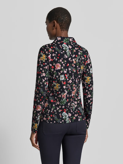 Frauenmodel trägt Slim Fit Hemdbluse mit floralem Allover-Print von Marc Cain, schwarze Grundfarbe mit buntem Blumenmuster, Rückenlänge 59 cm, Ärmellänge 63 cm, elastischer Material-Mix, Ganzkörperansicht Rückansicht.