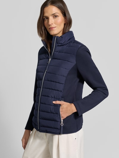 Vrouwenmodel draagt Steppjacke mit Kapuze und Reißverschlusstaschen van Christian Berg Woman Selection, donkerblauw, regular fit, opstaande kraag, rits- en steekzakken, gladde en gewatteerde texturen, voorzijde, halfhoge opname.