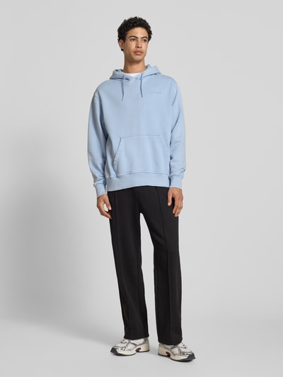 Männermodel trägt schwarze Sweatpants mit Längsnähten und Label-Stitching von CHAMPION aus Baumwoll-Mix, Relaxed-Fit, Ganzkörperansicht von vorne.