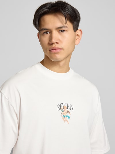 Männermodel trägt T-Shirt mit überschnittenen Schultern von REVIEW, Reine Baumwolle, Lockerer-Schnitt, Rundhalsausschnitt, Label-Print, Nahaufnahme Oberkörper.