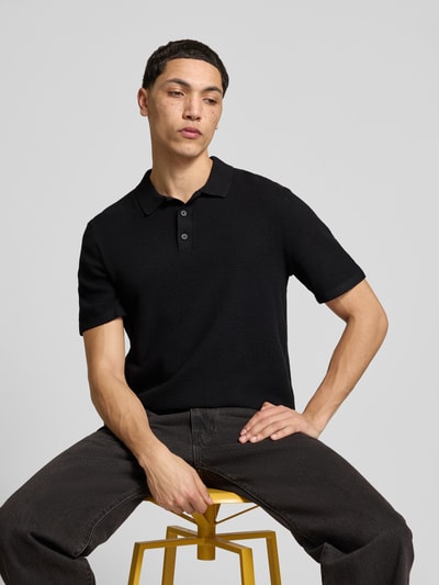 Männermodel trägt Regular Fit Poloshirt mit Strukturmuster Modell 'GEORGE' von Jack & Jones aus Baumwoll-Mix, schwarze Farbe, Knopfleiste, Rückenlänge bei Größe M 67 cm, Nahaufnahme Oberkörper.