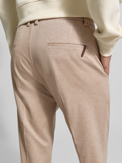 Männermodel trägt Regular Fit Hose aus Viskose-Mix Modell 'CIJUNO-O' von CINQUE in Beige mit Bundfalten, Detailaufnahme Rückansicht.