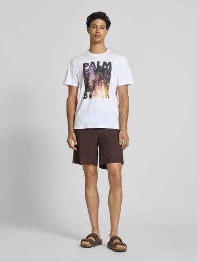 Männermodel trägt Regular Fit T-Shirt aus reiner Baumwolle Modell 'MAGDY LIFE' von Only & Sons, weiß mit Fotoprint, Ganzkörperansicht von vorne.