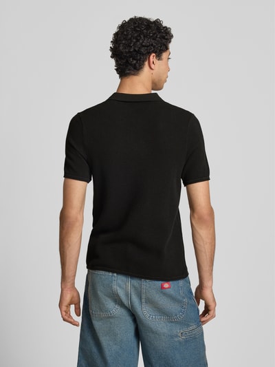 Męski model nosi Slim Fit Poloshirt mit Strukturmuster von REVIEW, czarna bawełna, krój slim fit, dekolt w serek, długość tyłu 66 cm, Ganzkörperansicht Rückansicht.