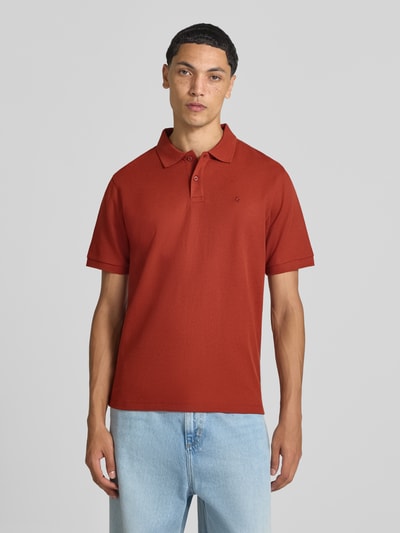Männermodel trägt Slim Fit Poloshirt mit Label-Stitching Modell 'AUSTIN' von JACK & JONES in Rot, stretchiger Baumwoll-Mix, Ganzkörperansicht von vorne.