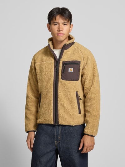 Männermodel trägt Teddyjacke mit Brusttasche Modell 'PRENTIS LINER' von Carhartt Work In Progress, beige, Reißverschlüsse, Ganzkörperansicht von vorne. Regular Fit, Stehkragen, Label-Patch, seitliche Reißverschlusstaschen, Rückenlänge 65 cm, Ärmellänge 51 cm.