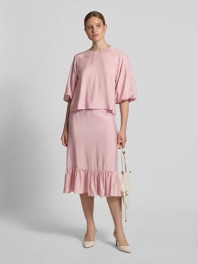 Frauenmodel trägt Regular Fit Bluse aus Viskose-Mix mit 3/4-Arm von Christian Berg Woman in zartem Rosa, lockere Passform, Rundhalsausschnitt, glatte Textur, Ganzkörperansicht von vorne.