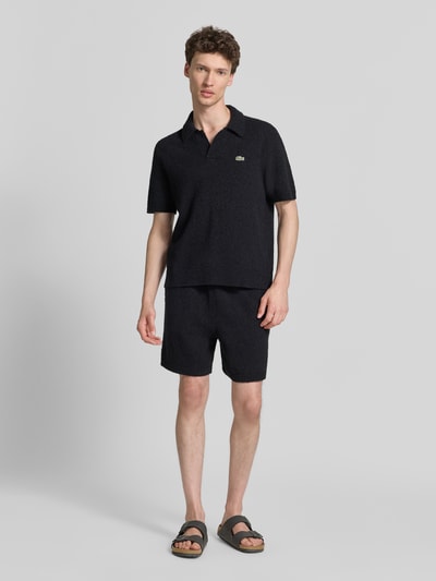 Männermodel trägt Relaxed Fit Sweatshorts aus Baumwoll-Mix von Lacoste in Schwarz mit elastischem Bund und Label Patch, Ganzkörperansicht von vorne.