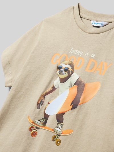 Mädchen trägt Kinder T-Shirt aus reiner Baumwolle von Mayoral, sandfarben, mit Aufdruck, gerader Schnitt, Rundhalsausschnitt, kurzärmelig, Ganzkörperansicht von vorne.