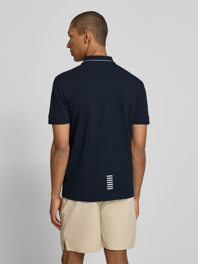Mężczyzna nosi Regular Fit Poloshirt mit Logo-Print od EA7 Emporio Armani, granatowy odcień, krój regular fit, widok całej sylwetki z tyłu.