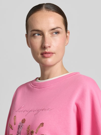 Frauenmodel trägt Oversized Sweatshirt aus reiner Baumwolle von miss goodlife, pink, Pailettenbesatz, Statement-Stitching, Nahaufnahme Oberkörper.