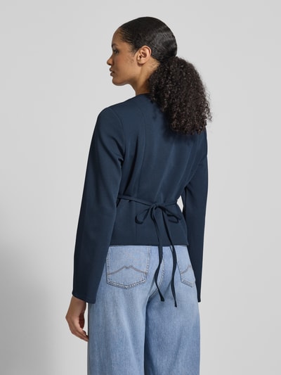 Frauenmodel trägt Blazer mit V-Ausschnitt Modell 'Simmi' von Neo Noir im Elastischer-Material-Mix, taillierte Passform, Wickel-Optik, Bindeband, Rückenlänge 52 cm, Brustweite 40 cm, Ärmellänge 63 cm, Dunkelblau, Ganzkörperansicht Rückansicht.