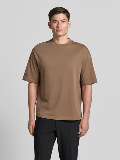 Männermodel trägt Relaxed Fit T-Shirt aus reiner Baumwolle Modell 'ASPEN' von SELECTED HOMME, Unifarbe Braun, Herren T-Shirt, Ganzkörperansicht von vorne.