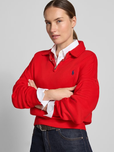 Modelka kobieca nosi czerwony sweter Regular Fit Pullover aus Baumwoll-Mix von Polo Ralph Lauren, gładka tekstura, prosty krój, widok na górną część ciała z przodu.