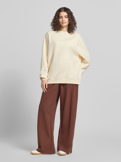 Frauenmodel trägt Oversized Sweatshirt mit Logo-Stitching Modell 'Pancake' von OH APRIL aus mieszanka bawełny w kolorze kremowym, krój oversized fit, okrągły dekolt, elastyczne wykończenia, Ganzkörperansicht von vorne
