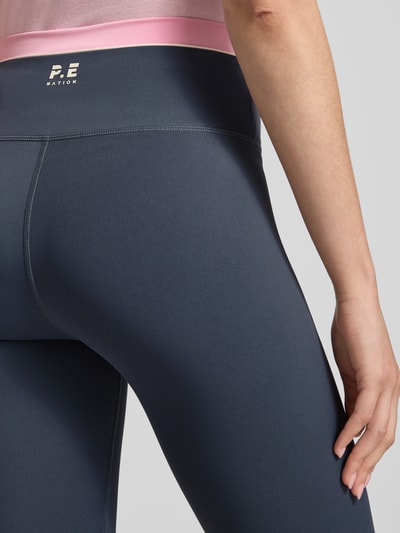 Frauenmodel trägt High Rise Leggings mit Logo von P.E Nation aus Material-Mix mit Stretch-Anteil, Kontraststreifen und Logo, Detailaufnahme