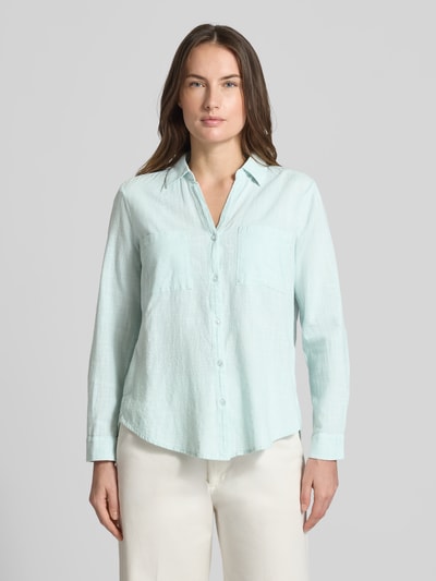 Vrouwenmodel draagt Regular Fit Hemdbluse aus reiner Baumwolle van Tom Tailor met allover Hahnentritt-motief, lichtblauw, fijne webstructuur, borstzakken, hemdkraag, v-hals, lange mouwen met turn-up optie, manchetten, afgeronde zoom, geheel van voren.
