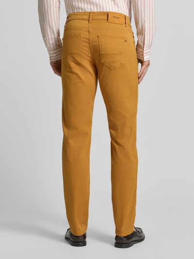 Männermodel trägt Stoffhose aus Baumwoll-Mix mit Viskose-Anteil Modell 'Cadiz' von Brax in Senfgelb, Ganzkörperansicht Rückansicht, Herren Stoffhose von Brax.