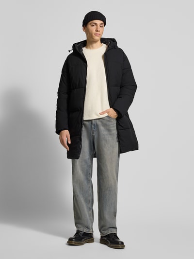 Mannenmodel draagt Regular Fit Steppmantel met Kapuze Modell 'Jorvester' van Jack & Jones, zwart, tweewegrits, statementprint, volledig frontaal.