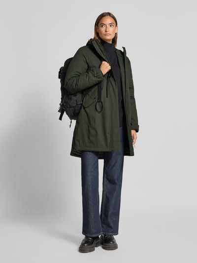 Frauenmodel trägt Parka mit Kapuze und Eingrifftaschen von camel active in Dunkelgrün, matte Struktur, Regular Fit, Ganzkörperansicht von vorne. Rückenlänge 93 cm, Schulterbreite 40 cm, Brustweite 53 cm, Ärmellänge 65 cm.