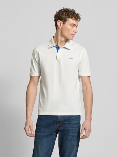 Männermodel trägt Regular Fit Poloshirt mit Logo-Stitching von Gant in Weiß, elastischer Baumwoll-Mix, Ganzkörperansicht von vorne.
