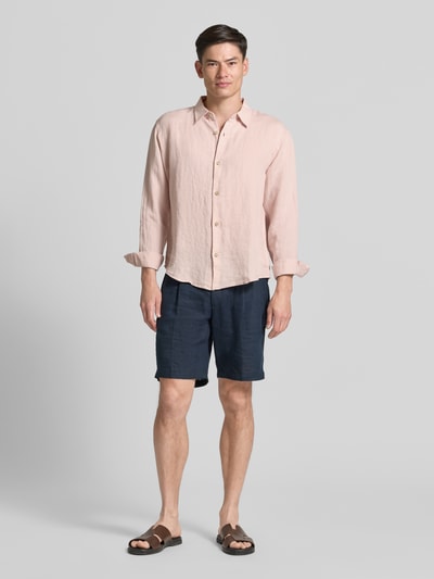 Männermodel trägt Regular Fit Leinenhemd mit Kentkragen von GAP in hellem Rosaton mit Knopfleiste, Regular-Fit, reine Leinenstruktur, Rückenlänge 71 cm, Schulterbreite 49 cm, Ärmellänge 64 cm, Ganzkörperansicht von vorne.