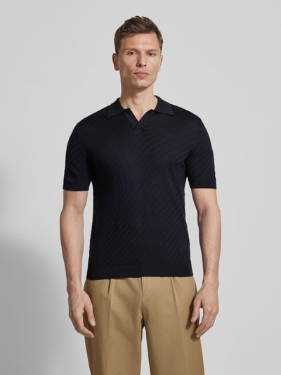 Männermodel trägt Slim Fit Poloshirt mit Lyocell-Anteil von Emporio Armani in Dunkelblau, Strick-Optik, Kurze Ärmel, Ganzkörperansicht von vorne.