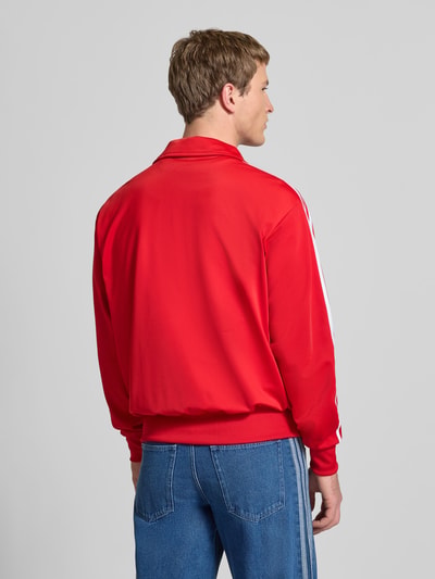 Männermodel trägt Sweatjacke mit Logo-Stitching Modell 'FIREBIRD' von adidas Originals in Rot, Gerader-Schnitt, Stehkragen, Rückenansicht.