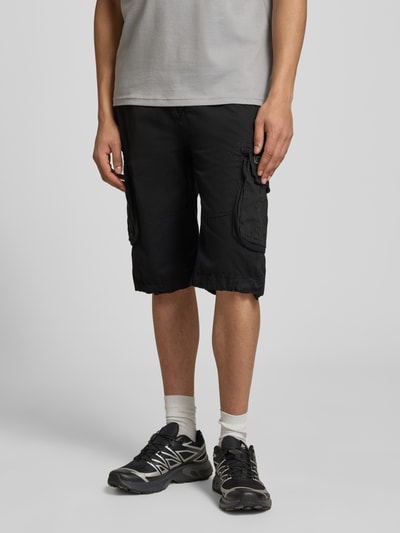 Männermodel trägt Bermudas mit Pattentaschen und Logo-Stitching von Alpha Industries aus Reine Baumwolle, Straight Fit, Schwarz, Ganzkörperansicht von vorne.