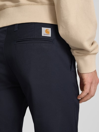 Männermodel trägt Skinny Fit Hose aus Baumwoll-Mix Modell 'SID' von Carhartt Work In Progress, dunkle Farbe, Nahaufnahme Rückansicht.
