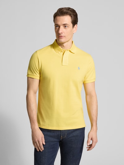 Männermodel trägt Regular Fit Poloshirt aus reiner Baumwolle von Polo Ralph Lauren in Gelb, unifarben, Logo-Detail, Piqué-Struktur, Ganzkörperansicht von vorne.