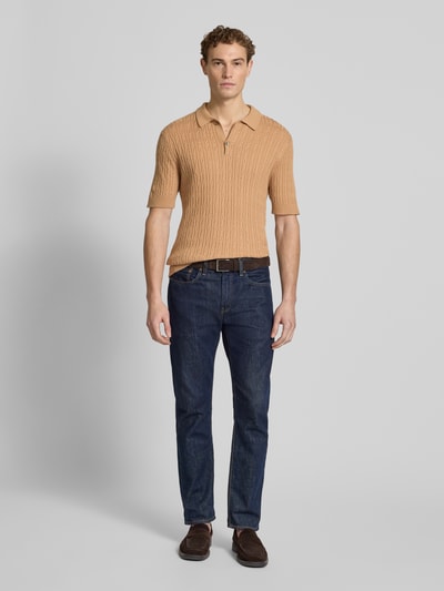 Männermodel trägt Slim Fit Kurzarm Pullover mit Kaschmir-Anteil in Strick-Optik von FTC-Cashmere, beigefarbener Baumwoll-Mix, Ganzkörperansicht von vorne.