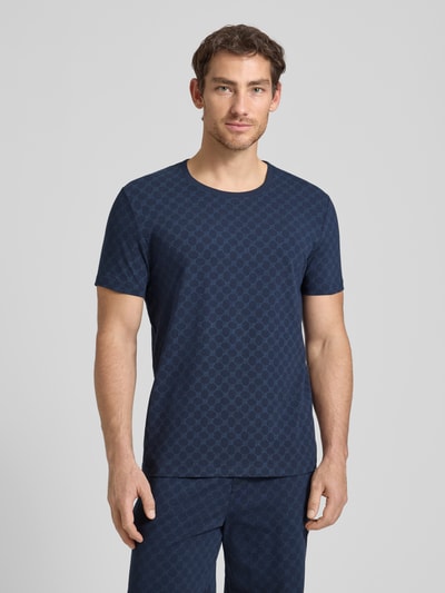 Männermodel trägt T-Shirt mit Logo-Muster und Rundhalsausschnitt von JOOP! Collection aus Baumwoll-Elasthan-Mix, Regular-Fit, dunkelblau, Ganzkörperansicht von vorne.