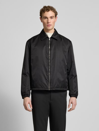 Männermodel trägt Regular Fit Blouson mit Logo-Muster Modell 'H-CRESTELL' von BOSS in Schwarz, Umlegekragen, Reißverschluss, Ganzkörperansicht von vorne.