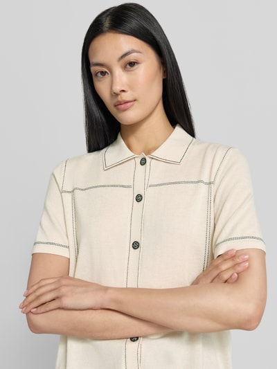 Frauenmodel trägt Regular Fit Hemdbluse mit Viskose-Kaschmir-Anteil von Marc Cain in Beige, Strick-Optik, Kurzarm, Nahaufnahme Oberkörper. Baumwoll-Mix, schwarze Knöpfe, Hemdblusenkragen.