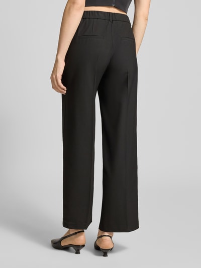 Vrouwenmodel draagt Wide Leg stoffen broek met persplooien van s.Oliver BLACK LABEL, effen kleuren, elastische boord, zij-steekzakken, achterzakken, riemlussen, haak- en verborgen ritssluiting. Ganzebody achteraanzicht.