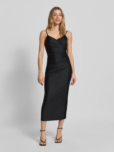 Frauenmodel trägt Cocktailkleid mit Spaghettiträgern und V-Ausschnitt von TROYDEN COLLECTION, schwarzer Satin, Körpernaher-Schnitt, Midikleid, Ganzkörperansicht von vorne.