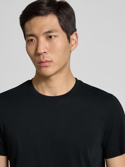 Männermodel trägt Regular Fit T-Shirt aus reiner Baumwolle von Tom Tailor in Optik: Unifarben mit Logo-Stitching, Rundhals, Kurzarm, Nahaufnahme Oberkörper.