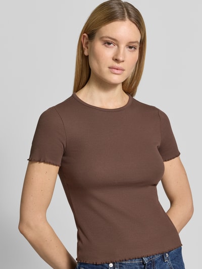 Modelka kobieca ma na sobie damski t-shirt z mieszanki bawełny o dopasowanym kroju, drobne prążkowanie, okrągły dekolt, falisty brzeg, długość tyłu w rozmiarze S: 52 cm, T-Shirt mit Wellensaum od Jake*s Casual, kolor brązowy, widok na górną część ciała z przodu.