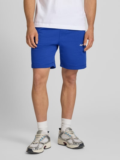 Mannenmodel draagt Sweatshorts met Stitching model 'KARL' van Jack & Jones, katoenmix, regular fit, elastische band, binnenbeenlengte 20 cm, bandwijdte maat M 44 cm, model van voren, detailopname onderlichaam.