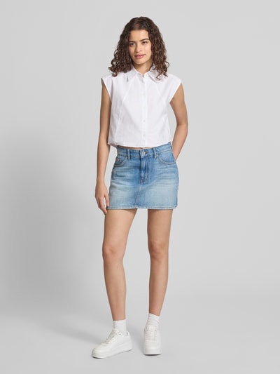 Frauenmodel trägt Straight Fit Mini-Rock aus reiner baumwolle im 5-Pocket-Design Modell 'GALANIE_2_B' von HUGO Blue, heller Jeansstoff und weißes Oberteil, Damen Jeansrock von HUGO, Ganzkörperansicht von vorne.