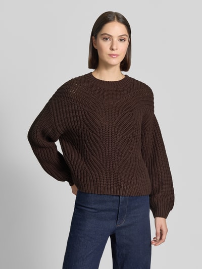 Frauenmodel trägt Relaxed Fit Strickpullover aus Baumwoll-Mix von Apricot in Braun, gerippte Abschlüsse, Rundhalsausschnitt, Ganzkörperansicht von vorne. Rückenlänge bei Größe S: 50 cm, Ärmellänge bei Größe S: 53 cm.