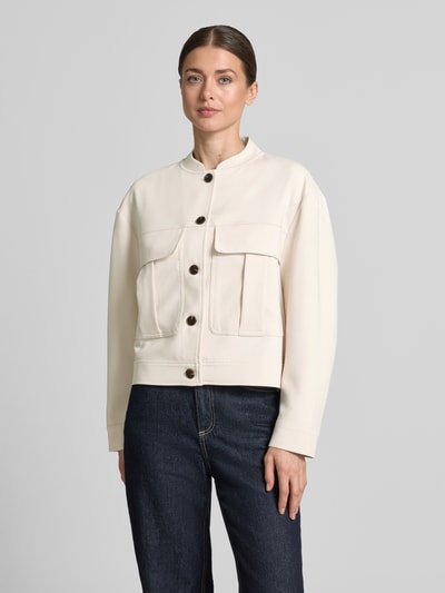 Kobieta modelka nosi kurtka Jacke mit Brusttaschen Modell 'Jalena' od OPUS, mieszanka materiałów z dodatkiem wiskozy, prosty krój, stójka, listwa guzikowa, kieszenie na piersi, kremowy kolor, tekstura gładka, długość tyłu w rozmiarze 36: 52 cm, szerokość ramion w rozmiarze 36: 41 cm, szerokość klatki piersiowej w rozmiarze 36: 58 cm, długość rękawów w rozmiarze 36: 55 cm, widok całej sylwetki od przodu