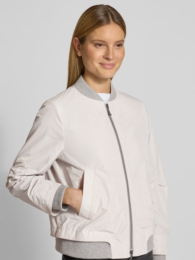 Modelka nosi Bomberjacke mit Zweiwege-Reißverschluss von Amber & June, kolor jasnoszary, krój regular fit, stójka, kieszenie, długość tyłu w rozmiarze 36: 59 cm, szerokość ramion w rozmiarze 36: 37 cm, szerokość w biuście w rozmiarze 36: 50 cm, długość rękawa w rozmiarze 36: 66 cm, faktura gładka, ujęcie z przodu – zbliżenie na górną część ciała.