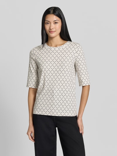 Kobiece model nosi Regular Fit T-Shirt mit Allover-Logo-Print von Marc Cain z mieszanki bawełny, okrągły dekolt, rękaw o dł. 1/2, długość tyłu 58 cm w rozmiarze 36, jasne kolory z nadrukiem, gładka faktura, widok całej sylwetki od przodu
