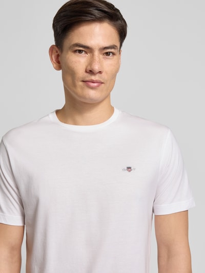 Męski model nosi Regular Fit T-Shirt mit Label-Stitching Model 'SHIELD' od GANT, jednokolorowy, bawełna, okrągły dekolt, długość tyłu 65 cm, widok na górną część sylwetki z przodu.
