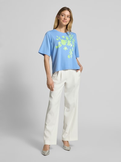 Frauenmodel trägt T-Shirt aus Viskose-Mix mit Paillettenbesatz von Milano Italy, Motiv-Print, Rundhalsausschnitt, Straight Fit, weiß-beige Hose, Ganzkörperansicht von vorne.