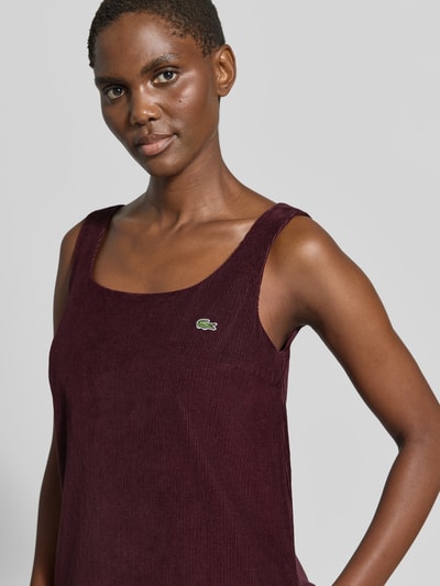 Vrouwenmodel draagt Slim Fit vrijetijdsjurk uit puur katoen van Lacoste in donker bordeaux met ribstructuur, close-up bovenlichaam. Dames vrijetijdsjurk van Lacoste